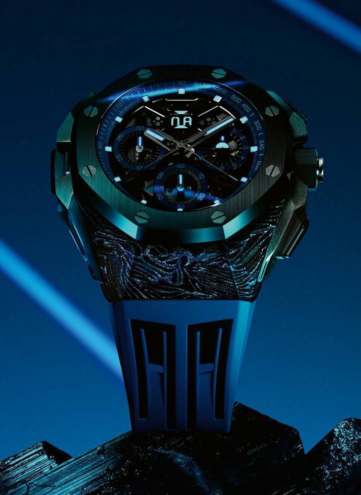 La caja ultraligera de carbono forjado de este nuevo Royal Oak Concept, que cuenta con pigmentos luminiscentes azules, se complementa con un bisel, una corona, pulsadores y un fondo de caja de cerámica negra. El reloj de dos tonos se realza con una esfera arquitectónica oscura con detalles en azul eléctrico.