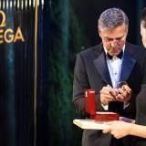 George Clooney autografiando la correa y la caja de presentación del Omega De Ville Hour Vision Annual Calendar que ha estado llevando.