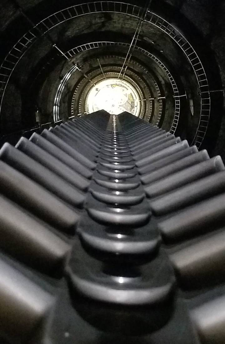 Vista desde la parte superior del pozo, mostrando la escalera en el borde y las ruedas dentadas en el centro.